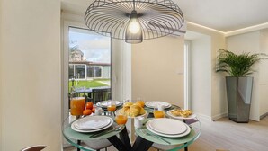 Uma área de refeições com mesa de vidro, pratos e itens de café da manhã.