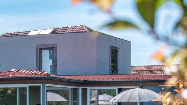 Uma casa moderna com piscina, portas de vidro deslizantes e área de estar externa.