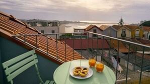 Eine Dachterrasse mit Frühstückstisch, mit Blick auf eine Küstenstadt.