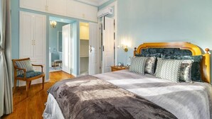 Ein Schlafzimmer mit einem großen Bett, einem Holzstuhl, einem Nachttisch und einem Kleiderschrank.