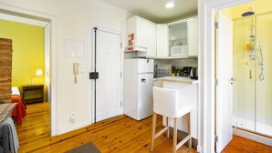 A compact kitchen with white cabinets, a refrigerator, and a small bar area. - Central Alfama Hideaway perfect to explore Lisbon (Lisboa)
