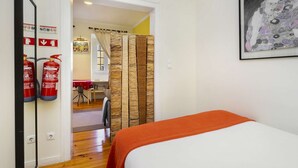 A hotel room with a bed, a fire extinguisher, a mirror, and a framed artwork on the wall. - Central Alfama Hideaway perfect to explore Lisbon (Lisboa)