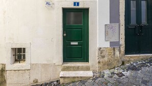 A building with a green door marked with the number 1, a small window with a metal bar, and a stone step leading to the door. - Central Alfama Hideaway perfect to explore Lisbon (Lisboa)
