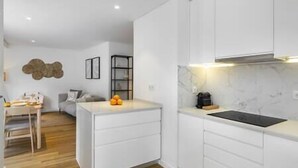 A modern kitchen with white cabinetry, a marble countertop, and a built-in oven.
