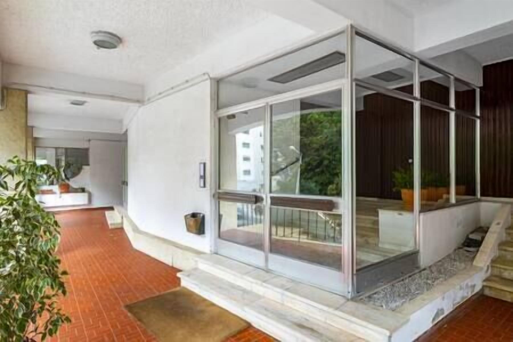 A modern interior with a glass-enclosed balcony, a staircase, and a potted plant.