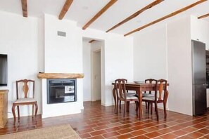 Un comedor con mesa y sillas de madera, horno empotrado y refrigerador.