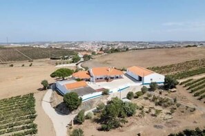 Vista aérea de una propiedad con un edificio grande, campos cercanos y cielo despejado.