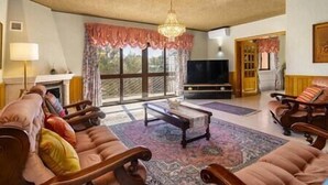 A living room with a fireplace, a television, and a large window with curtains.