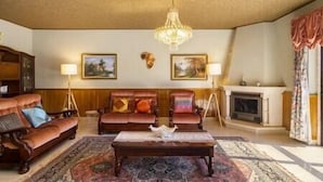 A traditional living room with a fireplace, leather sofas, a coffee table, and two wall-mounted lamps.