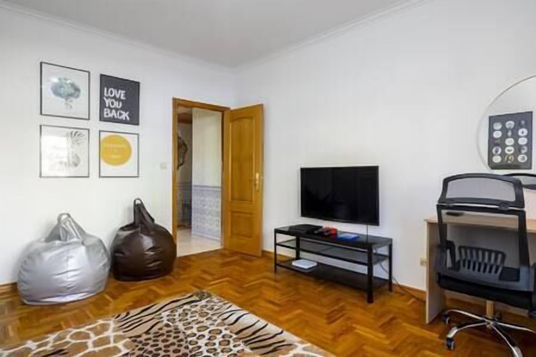 Een kamer met een televisie, een bank, een salontafel en een vloerkleed met zebraprint.