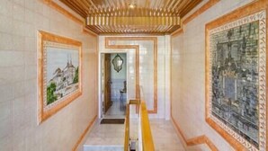 A hallway with a wooden ceiling, tiled walls, and framed artwork.