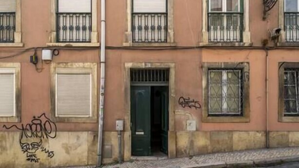 Um edifício de vários andares com janelas protegidas por grades e entrada no andar térreo.
