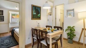 Uma sala de jantar com mesa, cadeiras, luminária e planta em vaso.