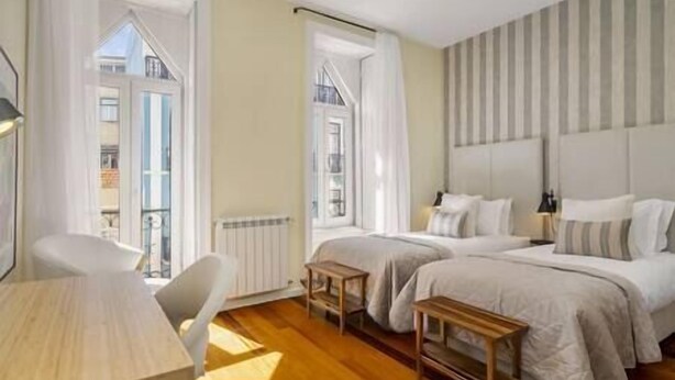 Una habitación de hotel con dos camas, una mesa de madera y una silla.