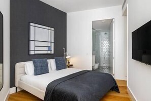 A modern bedroom with a bed, a wall-mounted TV, and a shower area. - Exclusive City Hideaway w/ Outdoor Space for Pets (Lisboa)