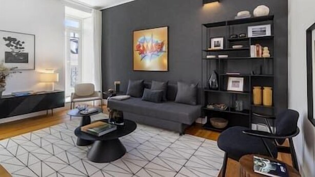 Ein modernes Wohnzimmer mit grauem Sofa, Couchtisch und Bücherregal.