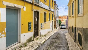 Eine enge Kopfsteinpflasterstraße, gesäumt von gelben Gebäuden mit sichtbaren Hauseingängen und Fenstern.