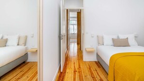 Ein modernes Hotelzimmer mit zwei Betten, Holzboden und einem hellen, offenen Design.