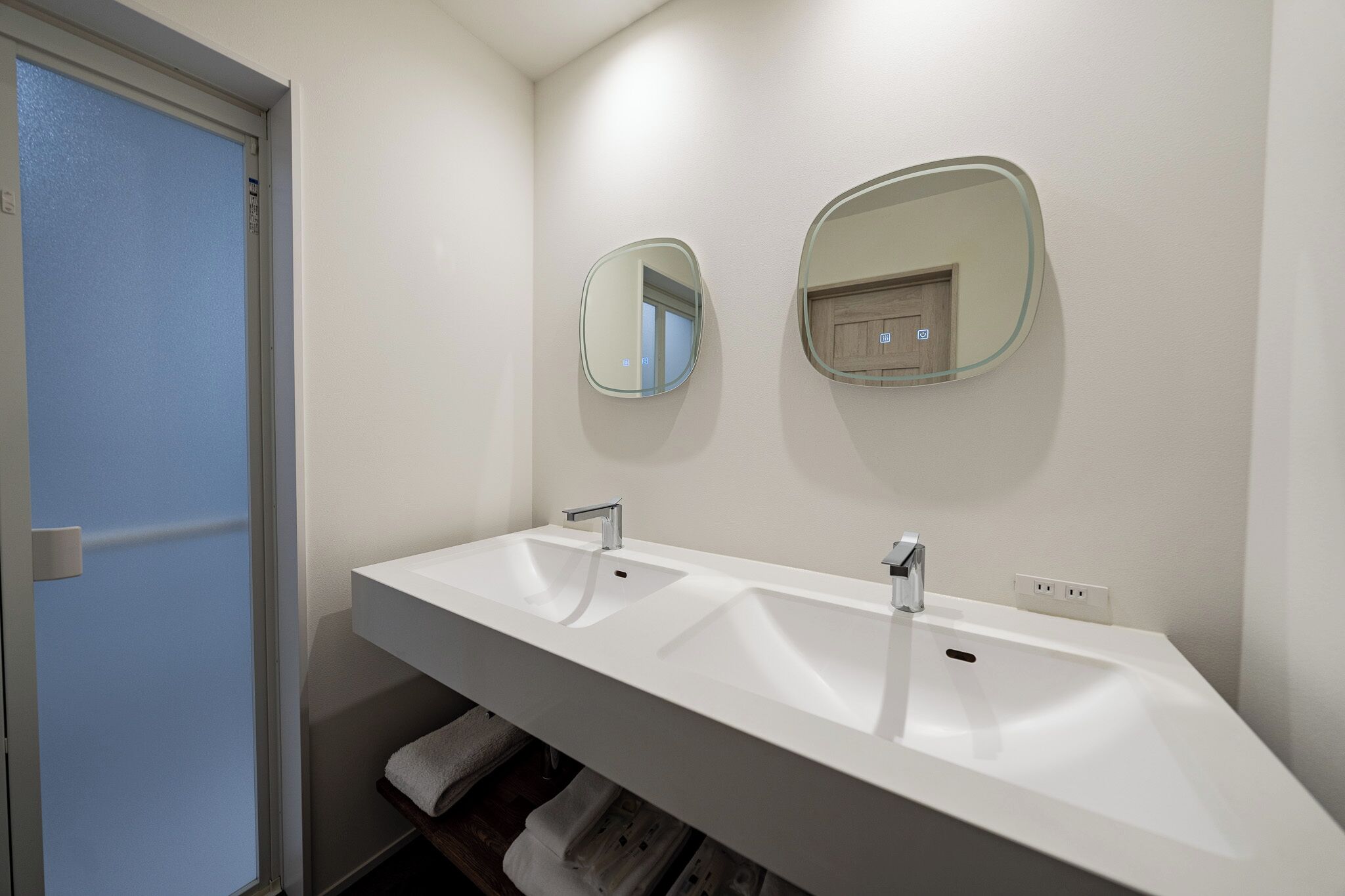 Une salle de bain moderne avec un lavabo blanc, deux miroirs et un porte-serviettes.