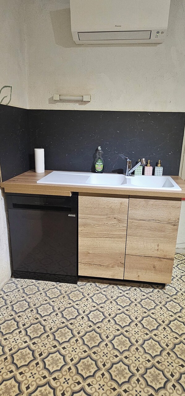 Una cocina con encimera blanca, lavavajillas negro y un armario de madera.