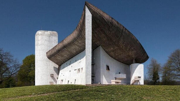 A modern building with a unique architectural design, featuring a large overhanging roof and a prominent central column.