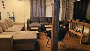 A living room with a sofa, a coffee table, a TV, and a wooden table with chairs.