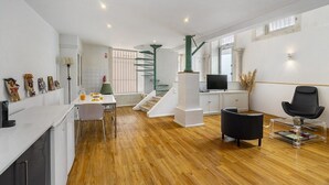 Un espacio habitable moderno con cocina, comedor y una escalera que conduce a un nivel superior.