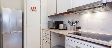 A compact kitchen with a stainless steel refrigerator, a microwave, a coffee maker, and a dishwasher.