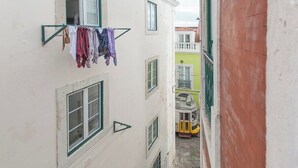 Een smalle steeg met gebouwen aan beide zijden, een waslijn met kleding en een gele tram op de achtergrond.