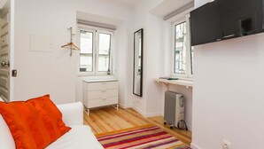A bedroom with a bed, a dresser, a mirror, a radiator, and a TV. - Hidden Gem I in Alfama perfect to explore Lisbon (Lisboa)