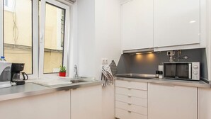 A compact kitchen with white cabinets, a microwave, a kettle, and a small sink. - Hidden Gem I in Alfama perfect to explore Lisbon (Lisboa)