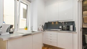 Una cocina moderna con gabinetes blancos, un microondas y una tetera sobre la encimera.