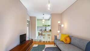 Un salon moderne avec un canapé, un téléviseur et une cuisine en arrière-plan.