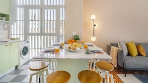Une cuisine moderne avec un coin repas, un lave-linge et un canapé avec des coussins.