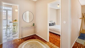 Une chambre à coucher avec un lit, une table de chevet et un miroir. Le sol est en bois et il y a un tapis.