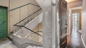 Un escalier orné de rampes en métal ouvragé et une porte verte.
