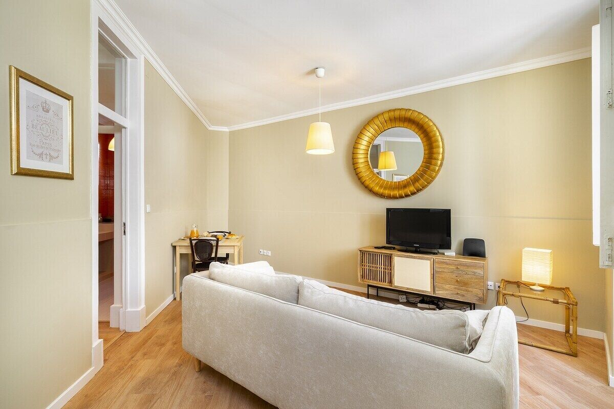 Ein modernes Wohnzimmer mit einer Couch, einem Fernseher, einem Schreibtisch und einem Spiegel an der Wand.