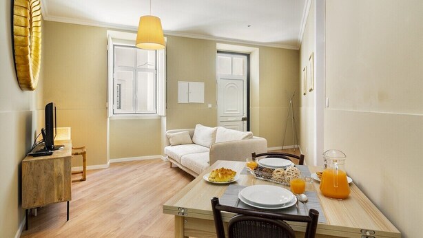 Un comedor con una mesa preparada para el desayuno, un sofá y un televisor sobre un mueble.