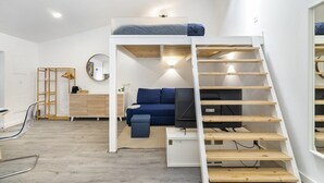 Una habitación pequeña con una litera, un escritorio, una silla y un espejo.