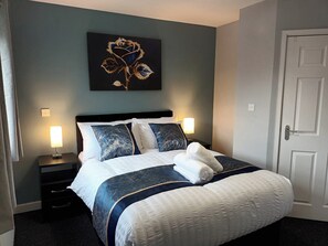 Una camera d'albergo con un letto, due comodini, un quadro appeso al muro e una porta.