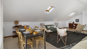 A dining area with a table set for breakfast, a sofa, and a chair.