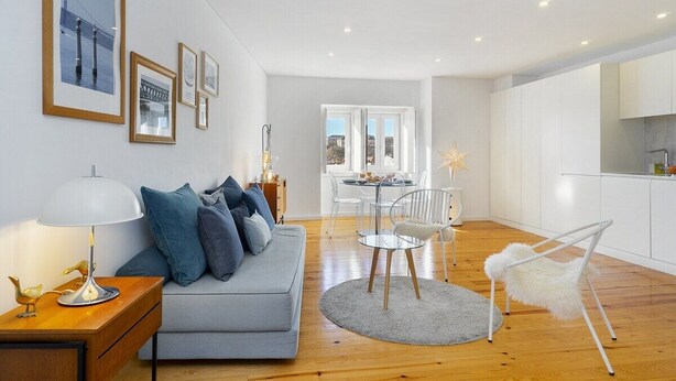 A modern living room with a sofa, a dining table, and chairs. There are framed pictures on the wall and a lamp on a side table. - Lisbon's Horizon Retreat: A View to Remember (Lisboa)