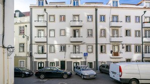 A multi-story residential building with balconies, a parking sign, and parked cars. - Lisbon's Horizon Retreat: A View to Remember (Lisboa)