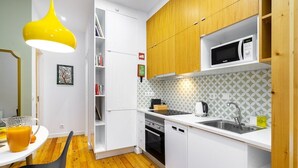 Une cuisine moderne avec des meubles blancs, un four à micro-ondes, un évier et un luminaire suspendu jaune.