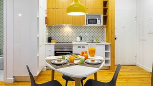 Une cuisine moderne avec des meubles blancs, un four à micro-ondes et un coin repas avec une table mise pour deux personnes.