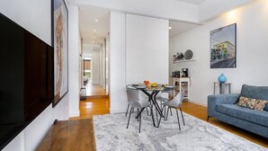 Una sala moderna con comedor, que incluye un sofá, una mesa con sillas y un jarrón azul sobre una mesita auxiliar.