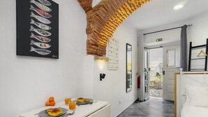 A hotel room with a bed, a table with breakfast, a wall art of fish, and a unique brick ceiling.