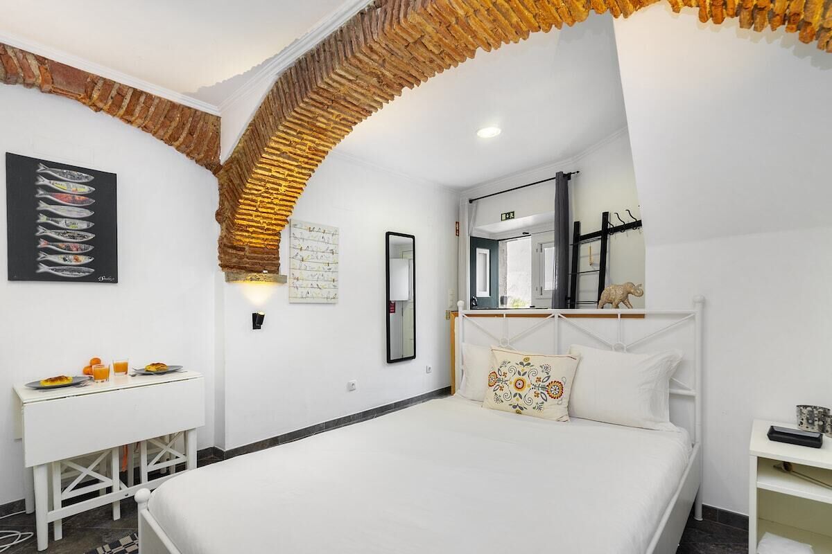 Een hotelkamer met een bed, een bureau met ontbijtartikelen, een spiegel en een muur met een visillustratie.