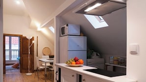 A compact kitchen with a white countertop, a microwave, a refrigerator, and a fruit bowl.
