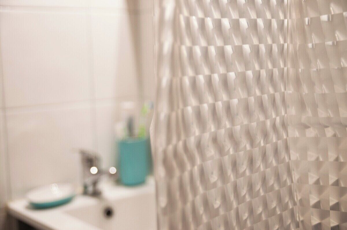 Een badkamer met een witte wastafel, een blauwe zeepdispenser en een wit toilet.